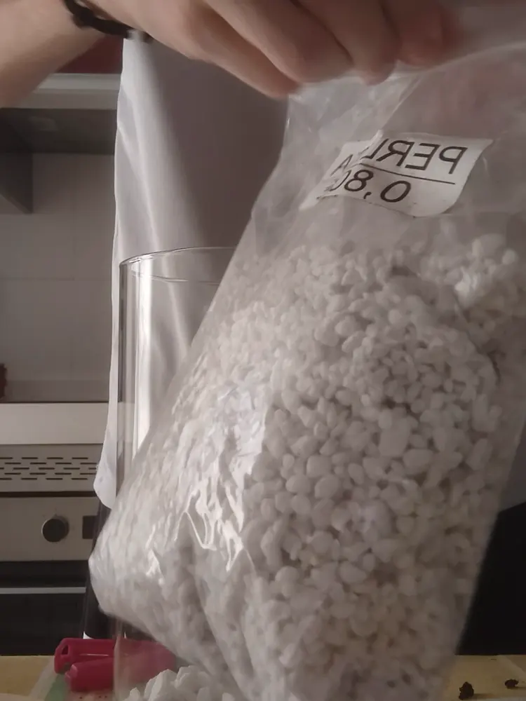 Echando perlita encima de la capa de marmolina dentro del tarro